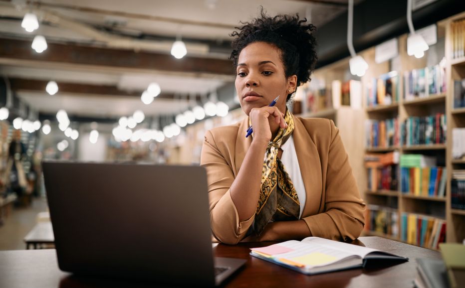 woman seated in a bookstore reading on her laptop