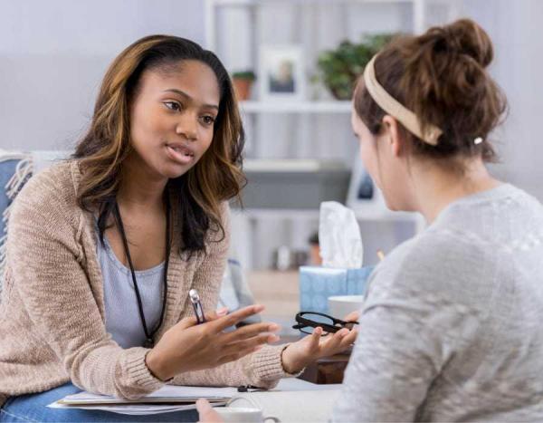 Una paciente y una profesional de la salud se sientan y hablan.