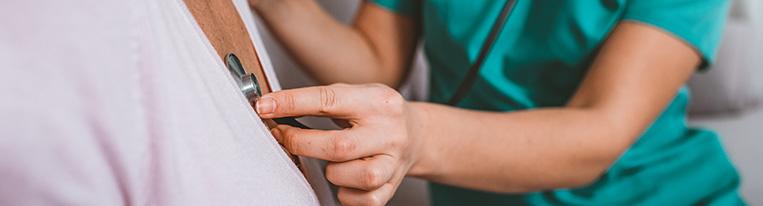 A health care provider listens to a patient's heartbeat with a stethoscope.